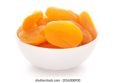 Close-up of orange colored dried apricot (prunus armeniaca) in a white ceramic bowl over white background.