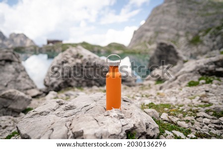 Close-up orange coloured water bottle in the mountains. Copy space. Zero waste, no plastic, sustainability. Lienz Dolomites, Austria. Natural beauty