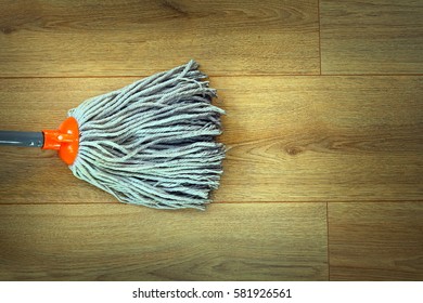closeup of orange mop head cleaning on beige wooden parquet