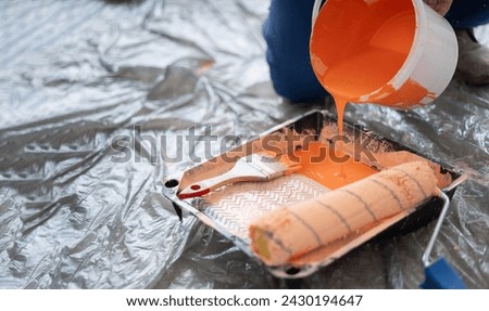 Close-up of orange paint pouring into tray. Tools for the painter and redecoration. Copy space [[stock_photo]] © 
