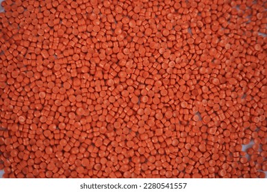 Close-up of orange plastic polymer granules. polymer plastic. compound polymer. PVC resin compounds. Tinted plastic granulate for injection moulding process.