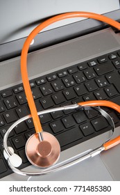 Close-up of orange stethoscope on laptop keyboard - Shutterstock ID 771485380