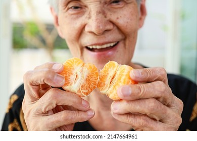 Closeup of organic fruit,old elderly holding juicy orange in hands,senior woman showing peeled tangerine,vitamin C from orange fiber,delicious and appetizing,healthy diet,health care,nutrition concept