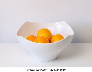 Closeup Of Organic Navel Oranges In White Bowl On Table Against Neutral Background (selective Focus)