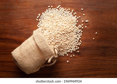 Close-up of Organic split polished white urad dal (Vigna mungo)   spilled out from a laying jute bag over wooden brown background.