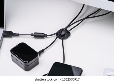 Close-up Of Organized Cable Holder On White Table With Charging Cables Connected To Wireless Devices