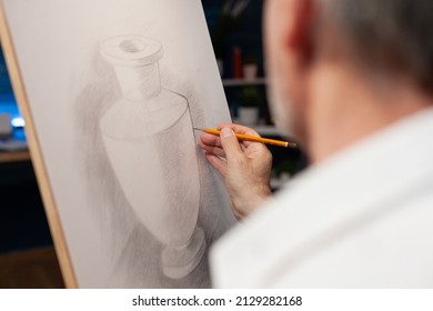 Closeup of original pencil drawing of vase on paper canvas done freehand by elderly man in creative workshop. Detailed view of sketch of still object done by inspired retired artist in home studio.