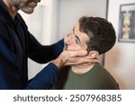 Close-up of an osteopath performing cervical manipulation and temporomandibular joint (TMJ) assessment on a male patient - Precise manual therapy technique for neck and jaw pain relief.