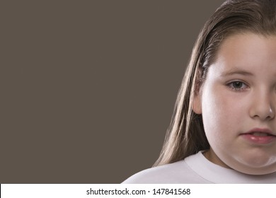 Closeup of an overweight serious girl against gray background