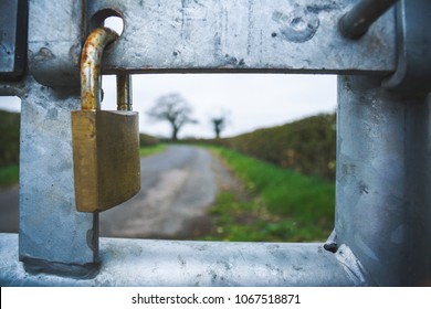 Closeup of a padlocked gate on the road to the countryside. No entry looking through to the countryside ahead. Where modern day meets mother nature