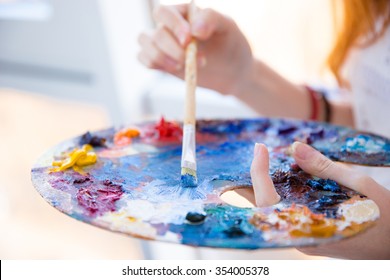 Closeup of paintbrush in woman hands mixing paints on palette - Shutterstock ID 354005378