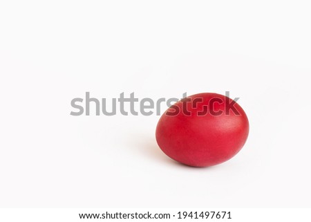 Close-up painted red egg settled in the middle of white background. Easter concept, copy space for text.