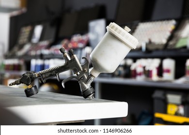 Closeup Of Paint-spray Gun On Table In Professional Car Painting Workshop