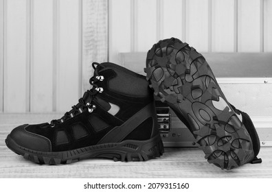Close-up pair black textile work boots for safe winter with steel cap,boot view of non-slip material sole on gray wooden background and metal tool box.Comfort flexibile safety workers concept,roofer - Shutterstock ID 2079315160
