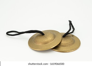 Closeup of a pair of finger cymbals lying on a white underground