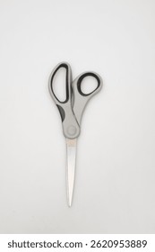 Close-up of a pair of grey and silver scissors on a white surface close-up photo macro view