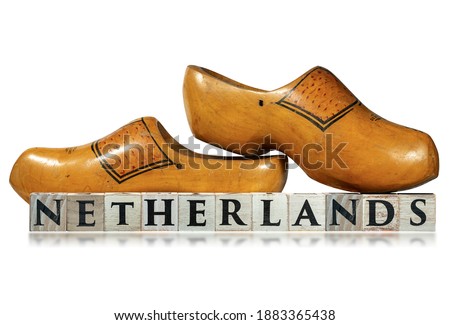 Closeup of a pair of wooden Dutch clogs and the text Netherlands, made of wooden blocks, isolated on white background with reflections.