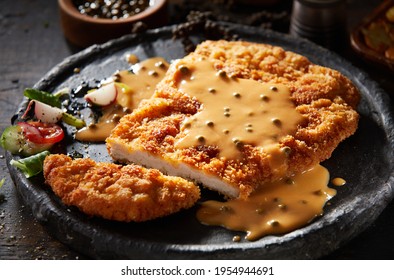 Closeup of palatable fried breaded veal escalope with aromatic creamy mustard sauce and fresh vegetable salad