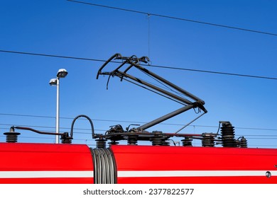 close-up of a pantograph of a red commuter train in cologne against a clear blue sky - Powered by Shutterstock