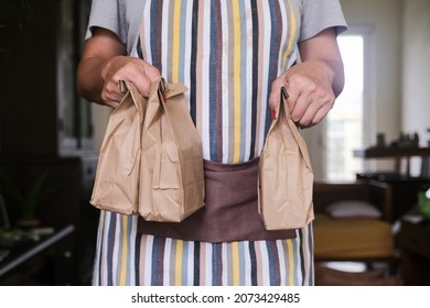 Close-up of paper bags containing food handed by a delivery woman. - Powered by Shutterstock