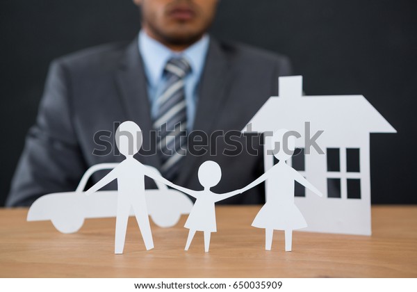 Close-up of paper cut out family chain with car and\
house at desk