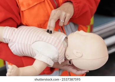 Close-up of paramedic demonstrating infant CPR on a mannequin for emergency training purposes. - Powered by Shutterstock