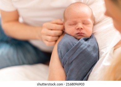 Close-up Of Parents Holding Neborn Baby Son Wrapped In Swaddle Blanket At Home.