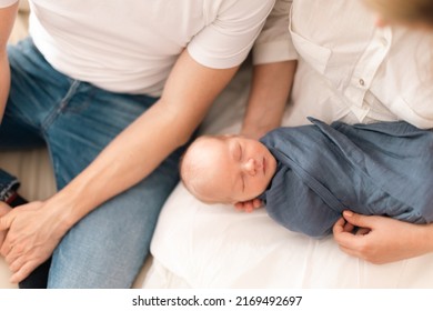 Close-up Of Parents Holding Newborn Baby Son Wrapped In Swaddle Blanket At Home.