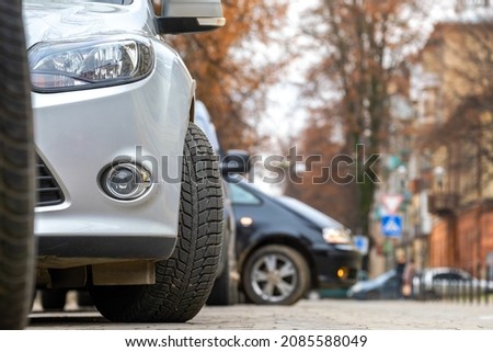Closeup of parked car on a city street side with new winter rubber tires.