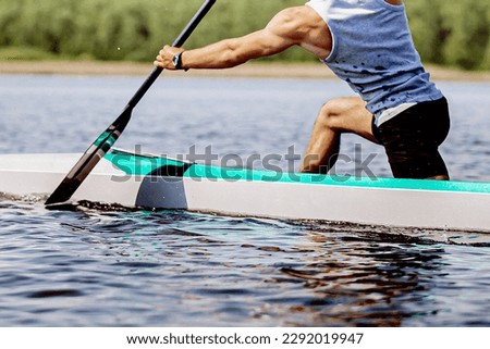 close-up part body male canoeist on canoe single rowing training on lake, muscular arm to hold paddle