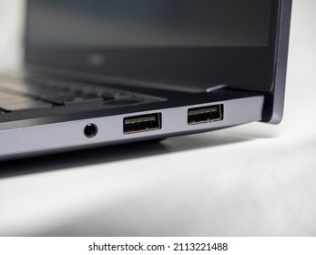 Close-up of a part of a laptop standing on a light background. Large USB ports on the laptop. Open laptop