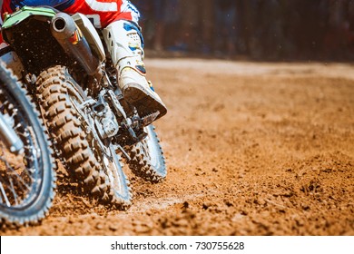 Close-up part of mountain bikes race in dirt track with flying debris during an acceleration in sunshine day time. Concept of focus between an accelerate in action sport