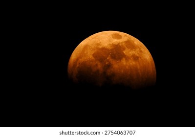 

Close-up of a partial lunar eclipse with warm orange hues and visible craters


A high-detail shot of a lunar eclipse showing the moon's surface in a deep orange and reddish glow. The craters and lunar geography are highlighted by the Earth's shadow, creating a dramatic and serene astronomical phenomenon against a black night sky.