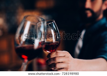 close-up partial view of friends clinking glasses of red wine