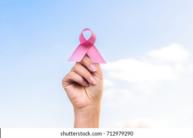 close-up partial view of hand holding breast cancer awareness ribbon - Powered by Shutterstock