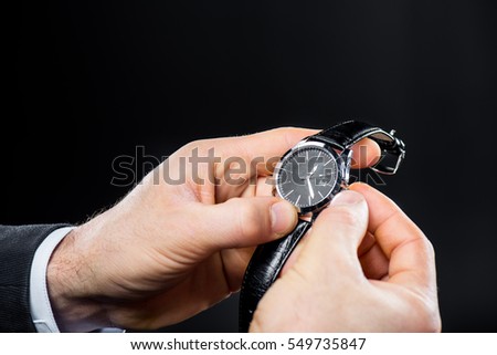 Close-up partial view of man dailing his handwatch isolated on black