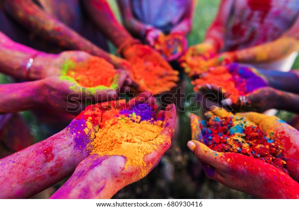 close-up partial view of young people\
holding colorful powder in hands at holi festival\
