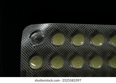A close-up of a partially empty blister pack of yellow tablets, with one pill missing from the packaging