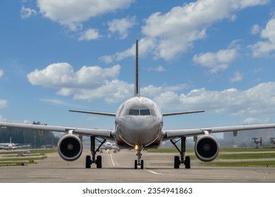 Close-up of a passenger plane on the taxiway at the airport against the backdrop of a beautiful cloudy sky, front view. A jet plane is preparing to take off