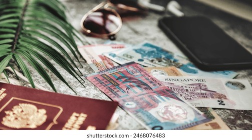 Close-up of passport, currency, sunglasses, smartphone, and palm leaf on desk, suggesting preparation for a journey. Travel essentials on textured surface. Travel vacation concept. Copy ad text space - Powered by Shutterstock