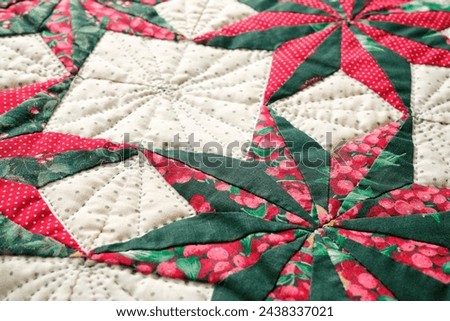 Closeup patchwork or quilt with christmas star motifs in green, red and white.
