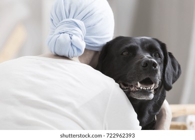 Close-up Of Patient With Cancer Hugging Black Dog During Animal Assisted Therapy