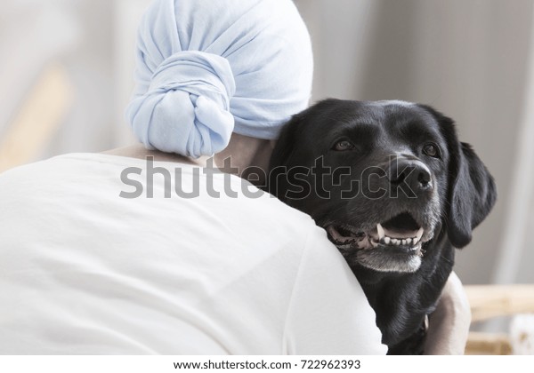Close-up of patient with cancer hugging black dog
during animal assisted
therapy