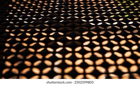 close-up of a patterned metal screen. The pattern consists of repeating geometric shapes that create a lattice-like structure. The screen is backlit, casting intricate shadows on a surface behind it - Powered by Shutterstock