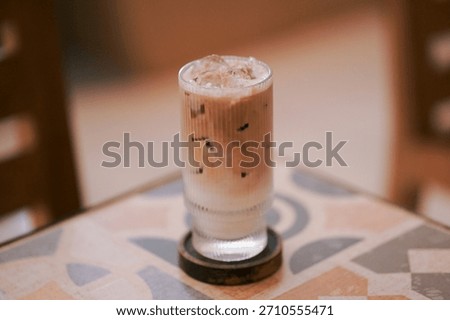 Close-up of a patterned mosaic tile tabletop showcasing a refreshing iced beverage in a textured glass, capturing the casual, sunlit, and aesthetic vibe of a contemporary urban cafe interior