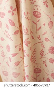 Closeup Of A Patterned Pink Textile Fabric. Cotton Cloth With Rosy Printed Botanical Linocut Pattern With Primitive Flowers, Leaves And Insects. Tea Towel, Dishcloth, Kitchen Towel In Warm Light.