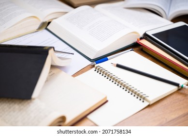 Closeup pencil on the notebook with many opened books on the desk, editing or rewrite the information from many reference book to create a new content - Shutterstock ID 2071758134