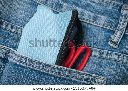 closeup of pencilcase and scissors on blue jeans pocket