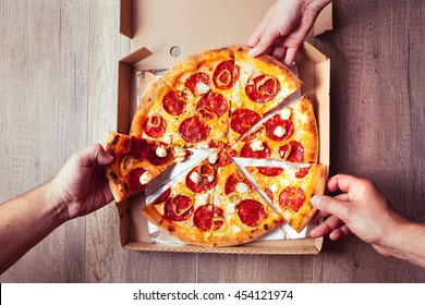 Close-up Of People Hands Taking Slices Of Pepperoni Pizza. 