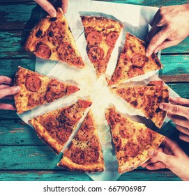 Close-up Of People Hands Taking Slices Of Pepperoni Pizza. Eating Food.  Group Of Friends Sharing Pizza Together. Fast Food, Friendship, Leisure, Lifestyle.